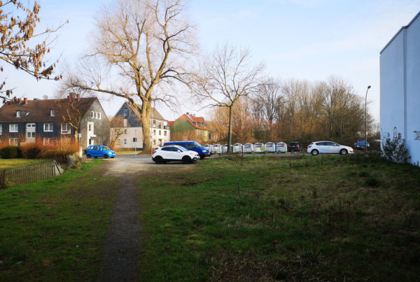 Blick auf Parkplatz und Wohnhäuser mit Grünfläche im Vordergrund