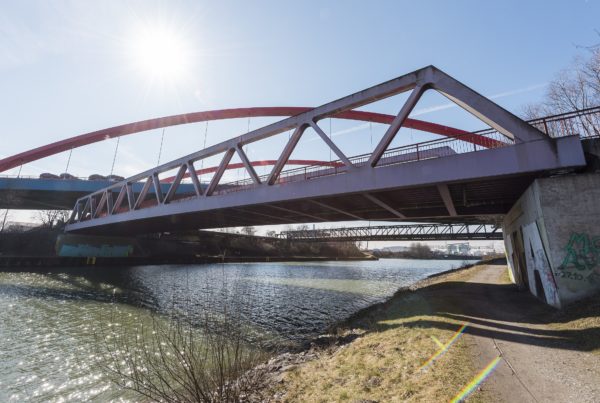 Ein Fluss fließt unter einer Brücke, blauer Himmel mit Sonnenschein