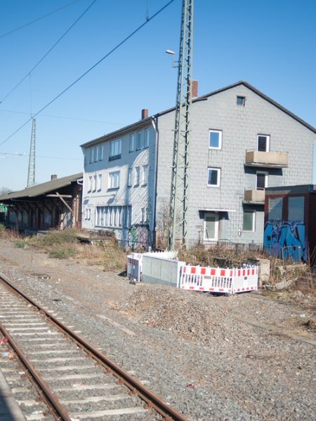 Blick auf eine Bahntrasse, rechts im Bild unsanierte Wohnhäuser