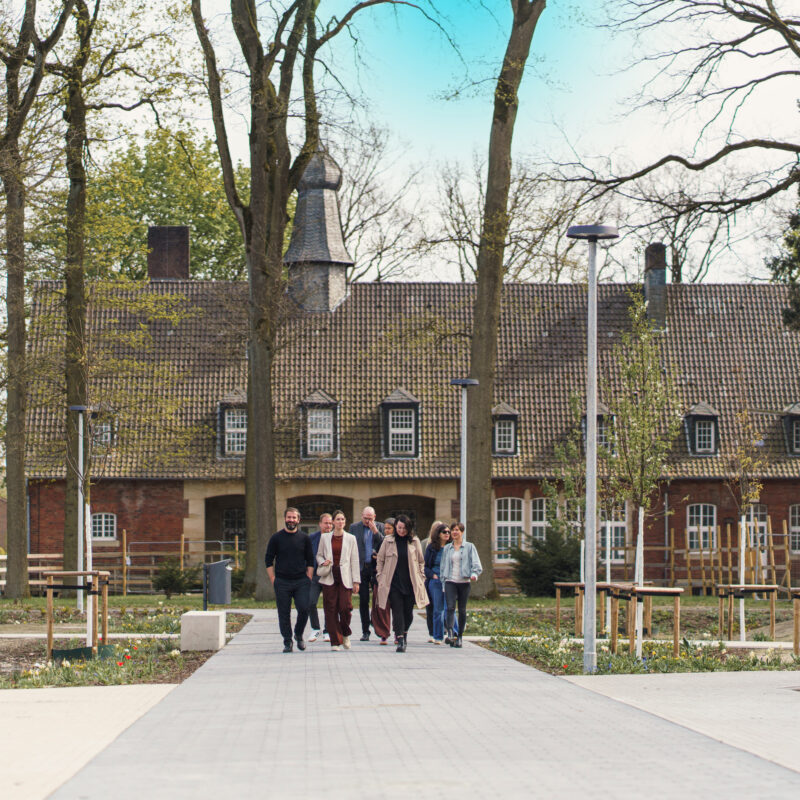 Die Bau- und Planungsgruppe unterwegs auf einer der Hauptverbindungsachsen des Areals, im Hintergrund das zukünftige Bürgerhaus.