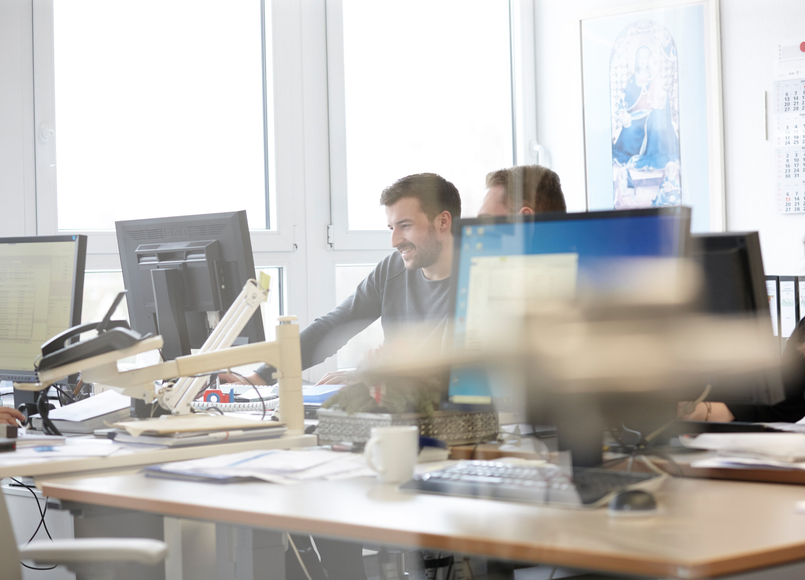 Arbeitssituation im Büro, zwei Kollegen sitzen zusammen am Schreibtisch und blicken auf den Monitor